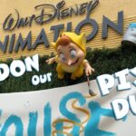 The Lost Boy figure from Back to Neverland paints an Open House banner beneath the Walt Disney Animation lettering at Disney's Hollywood Studios, on the title card for the Pardon Our Pixie Dust episode.