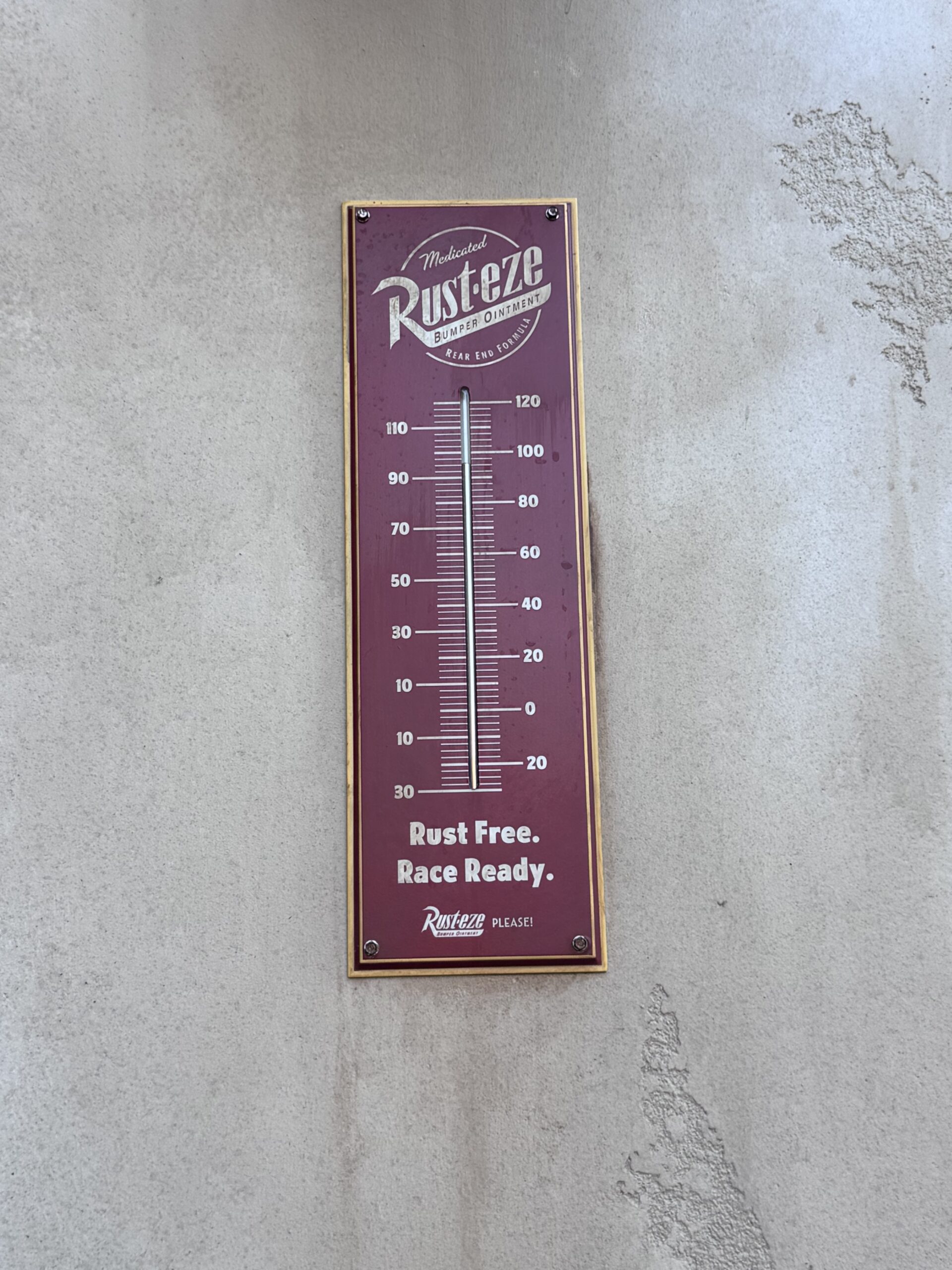 A Rust-eze Medicated Bumper Ointment thermometer reading Rust Free, Race Ready mounted on the Take-A-Brake Rest Stop building in Cars Land