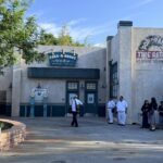 The Take-A-Brake Rest Stop restroom building in Cars Land at Disney California Adventure on its opening day, with the Pop N Patch Tire Repair mural and Stanley's Oasis water fountains