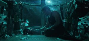 Robert Downey Jr. as Tony Stark sitting on the floor of a spacecraft beside his Iron Man helmet in Avengers: Endgame
