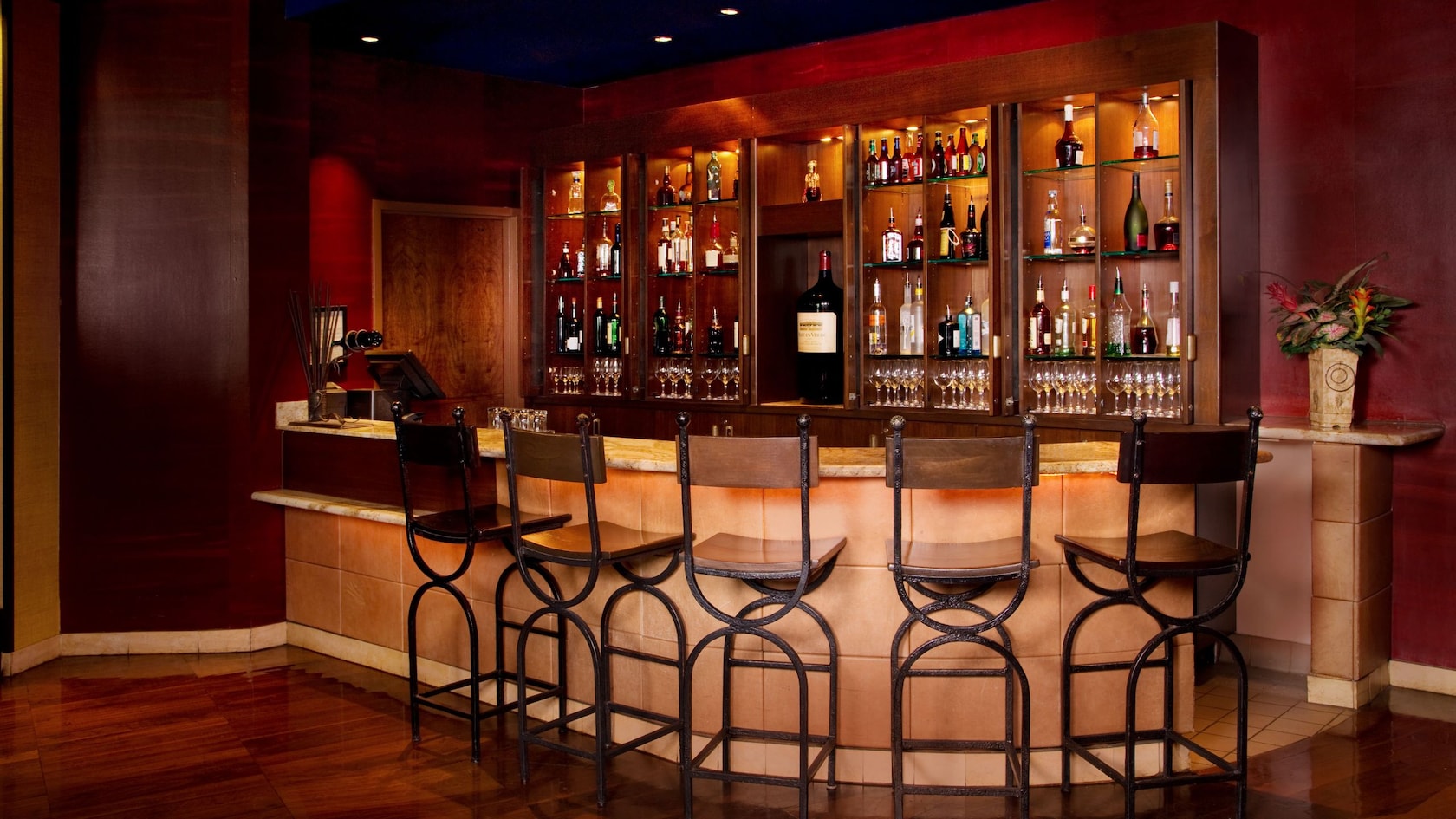 A bar with many bottles of wine, liquor and beer surrounded by barstools