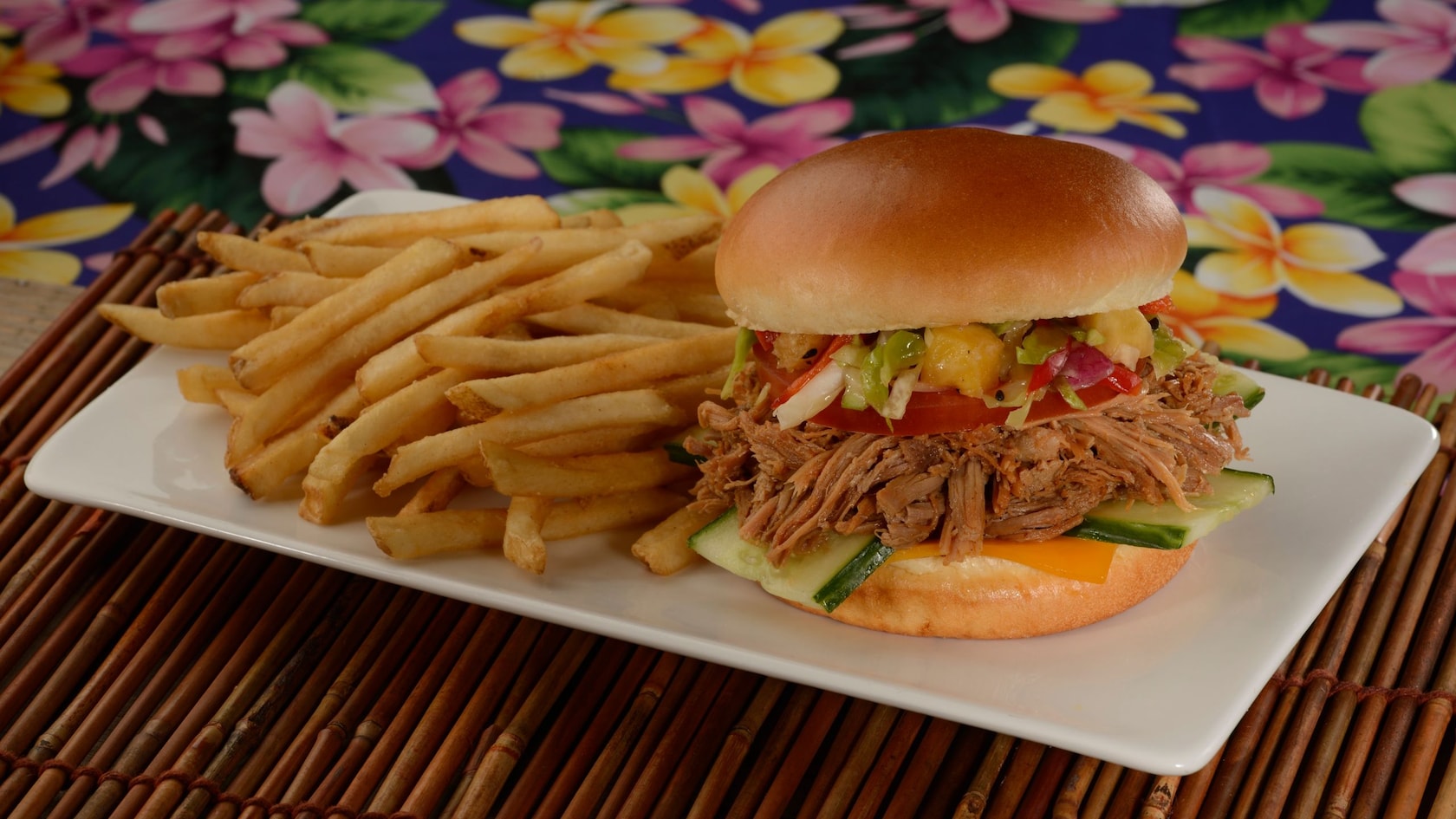 A pulled pork sandwich served on a plate with French fries