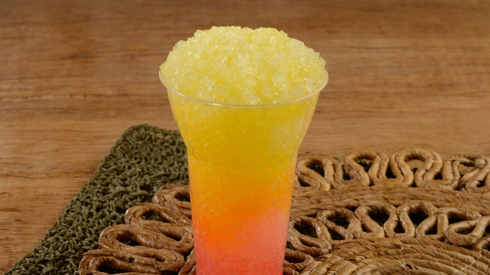 A large cup of Mango Passion Fruit Shaved Ice rests on a placemat