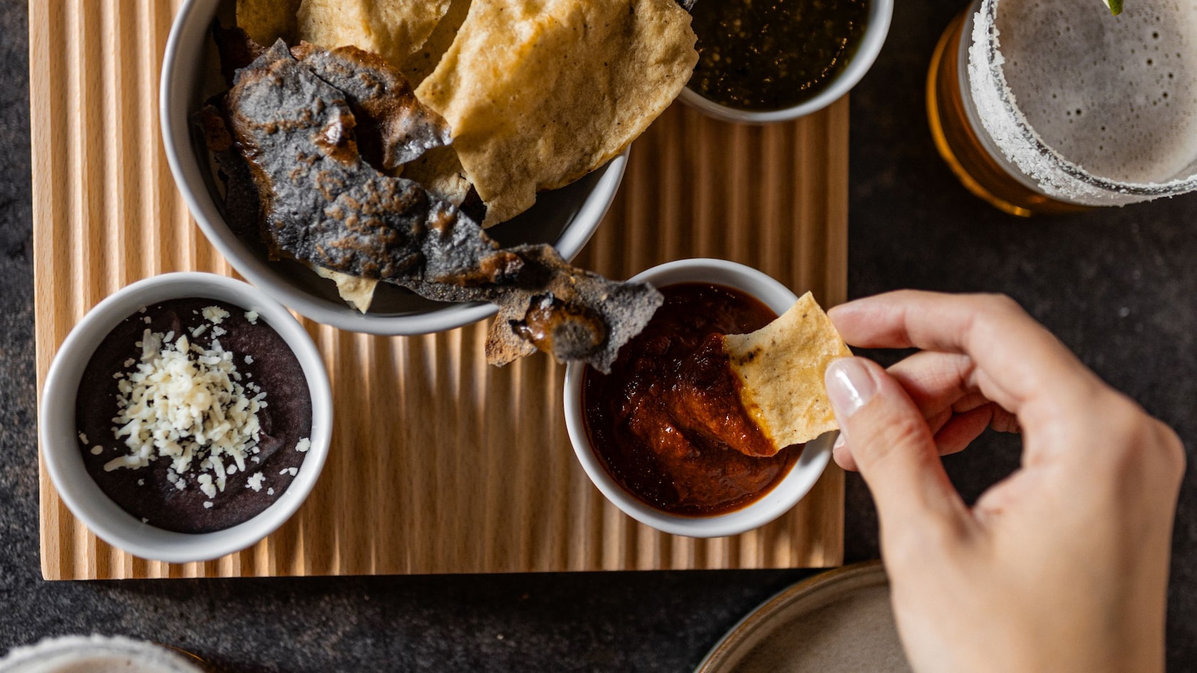 Tortilla chips with refried beans and an assortment of salsa dips