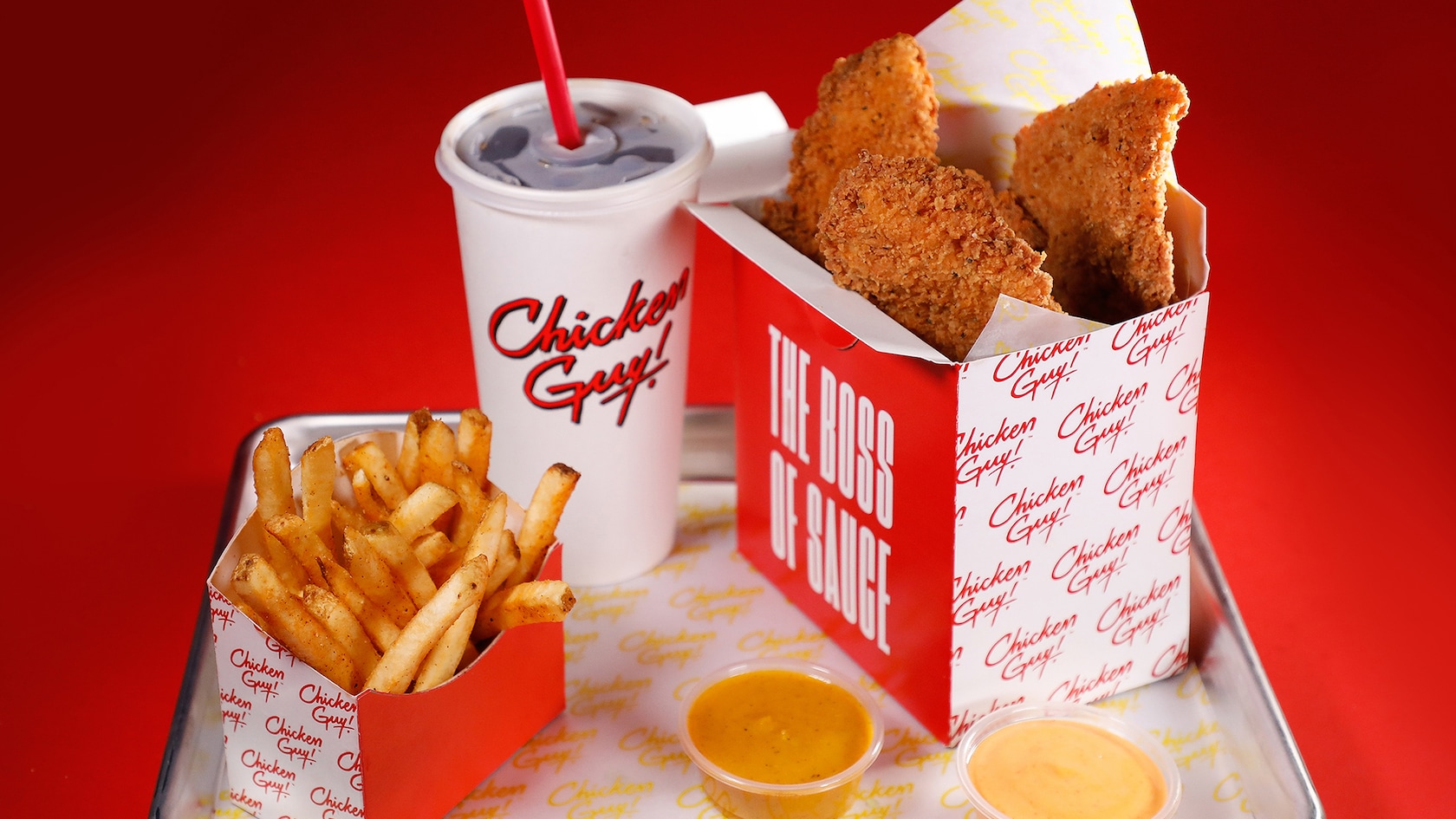 A fast food meal with french fries, a medium drink, sauce cup and chicken tenders
