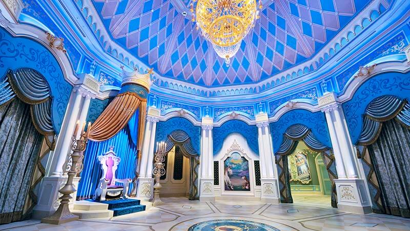 The Grand Hall of Cinderella's Fairy Tale Hall at Tokyo Disneyland, with a throne, chandelier and blue arched alcoves