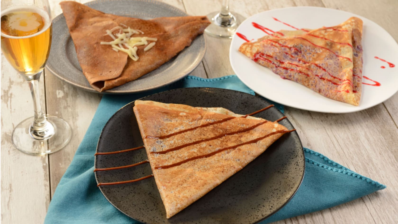 3 plates of crepes beside a flute of sparkling wine