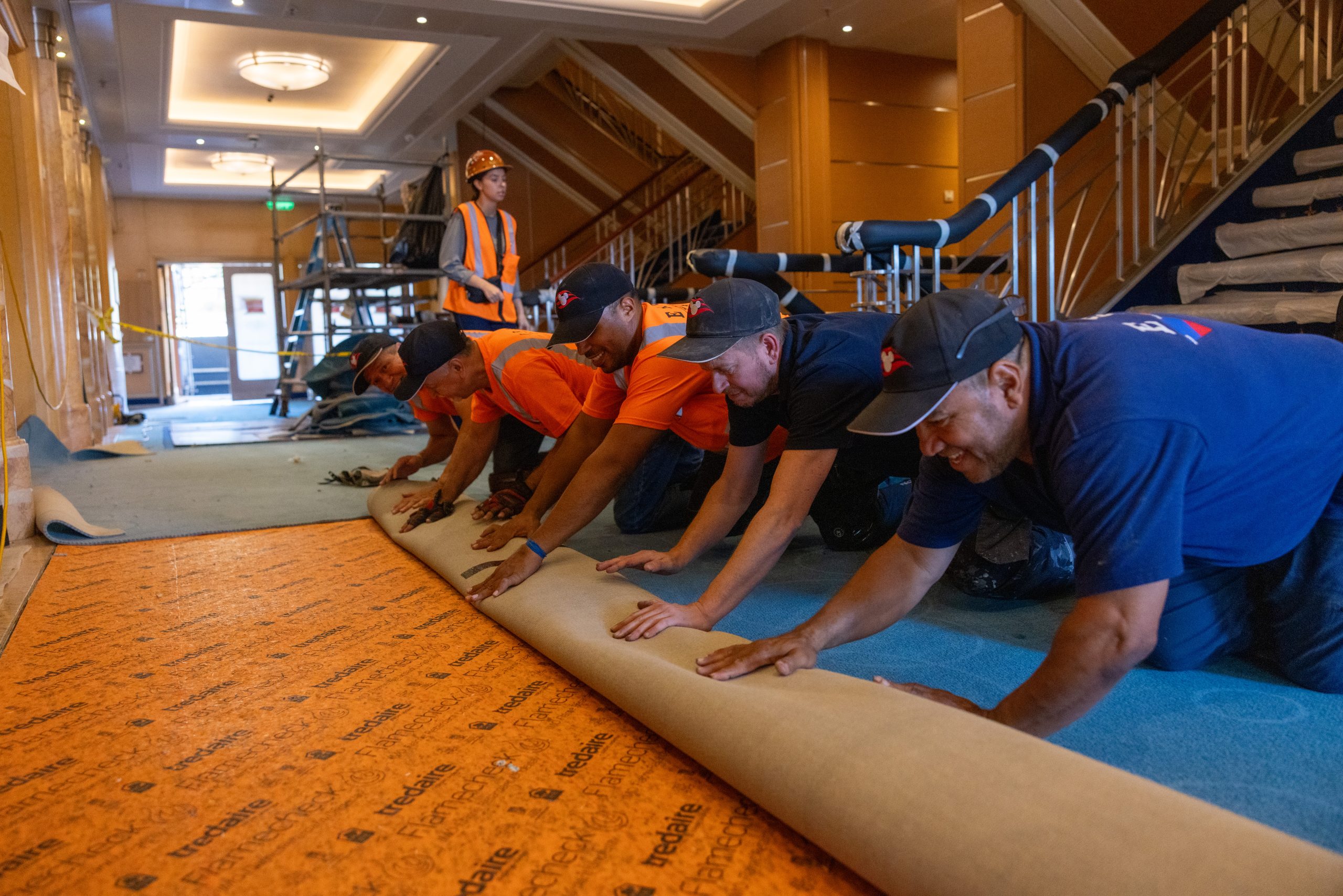 Workers roll out new carpet aboard a Disney Cruise Line ship during dry dock