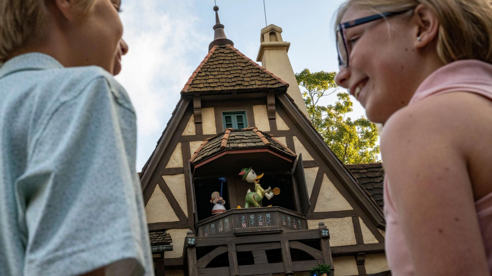 Guests looking up at a Germany pavilion clock tower during DuckTales World Showcase Adventure at EPCOT