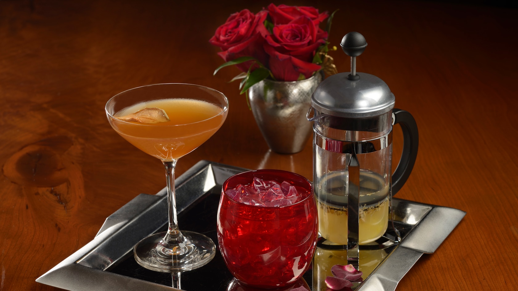 Three beverages being served on a tray next to a bouquet of roses