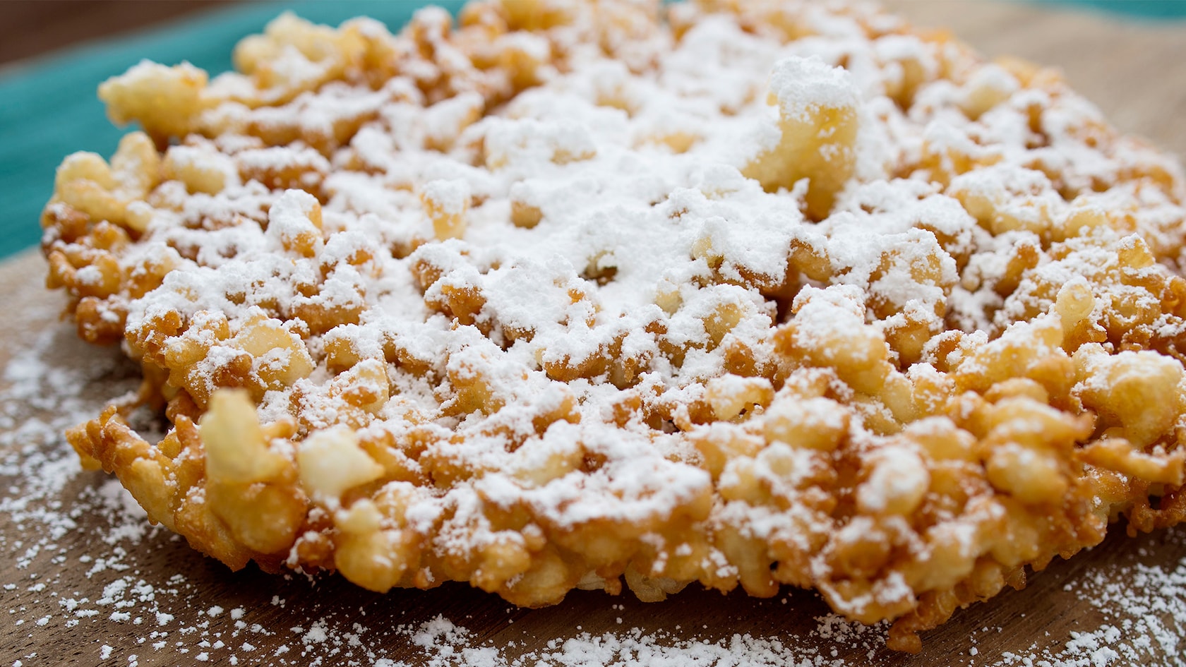 A crispy funnel cake dessert topped with powdered sugar