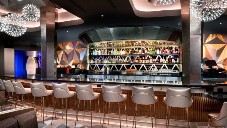 A bar and stools in front of liquor lined shelves at Geo 82 at Epcot