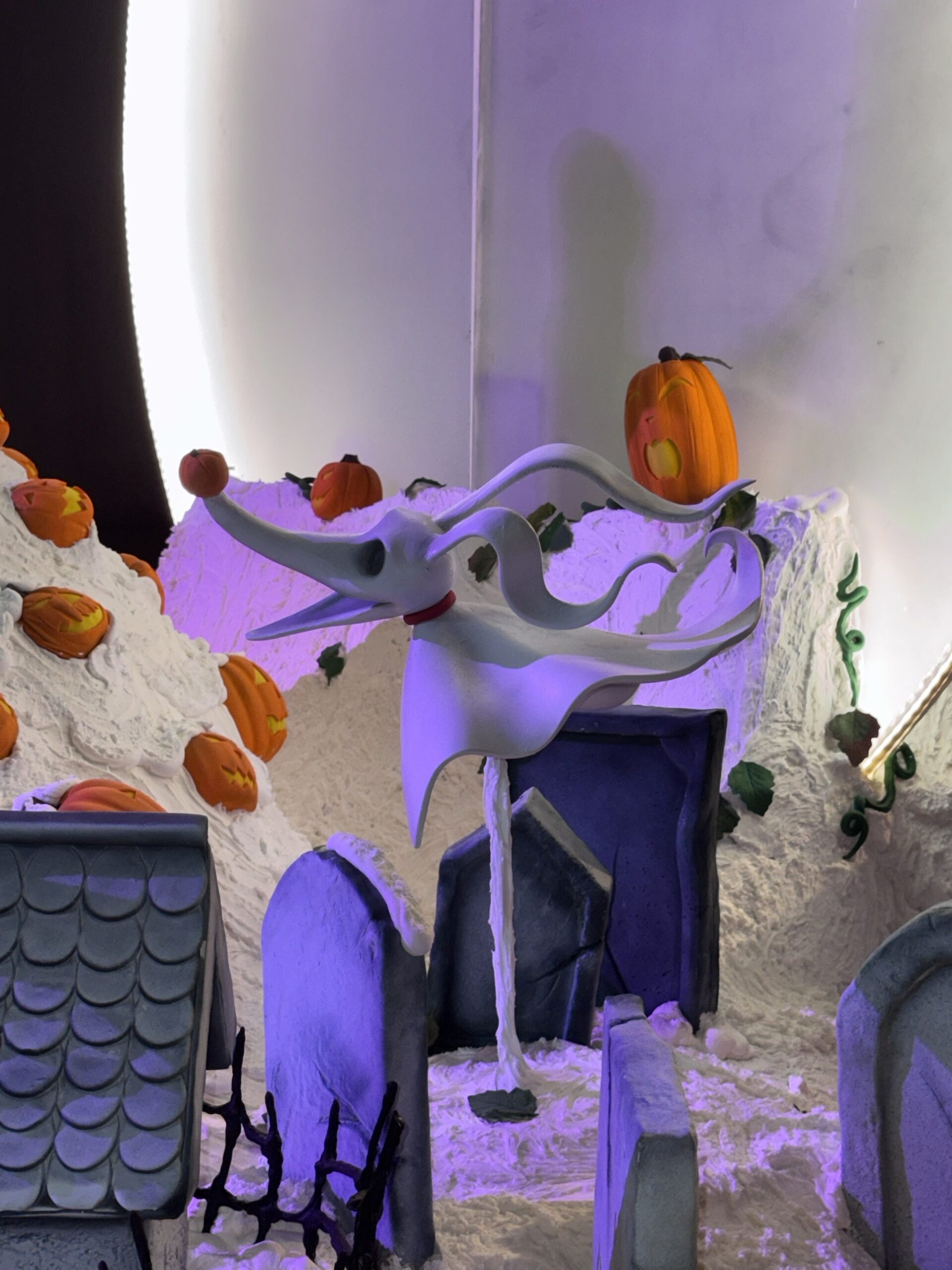 Zero the ghost dog confection figure with a small pumpkin on his nose floating above tombstones at the Grand Californian