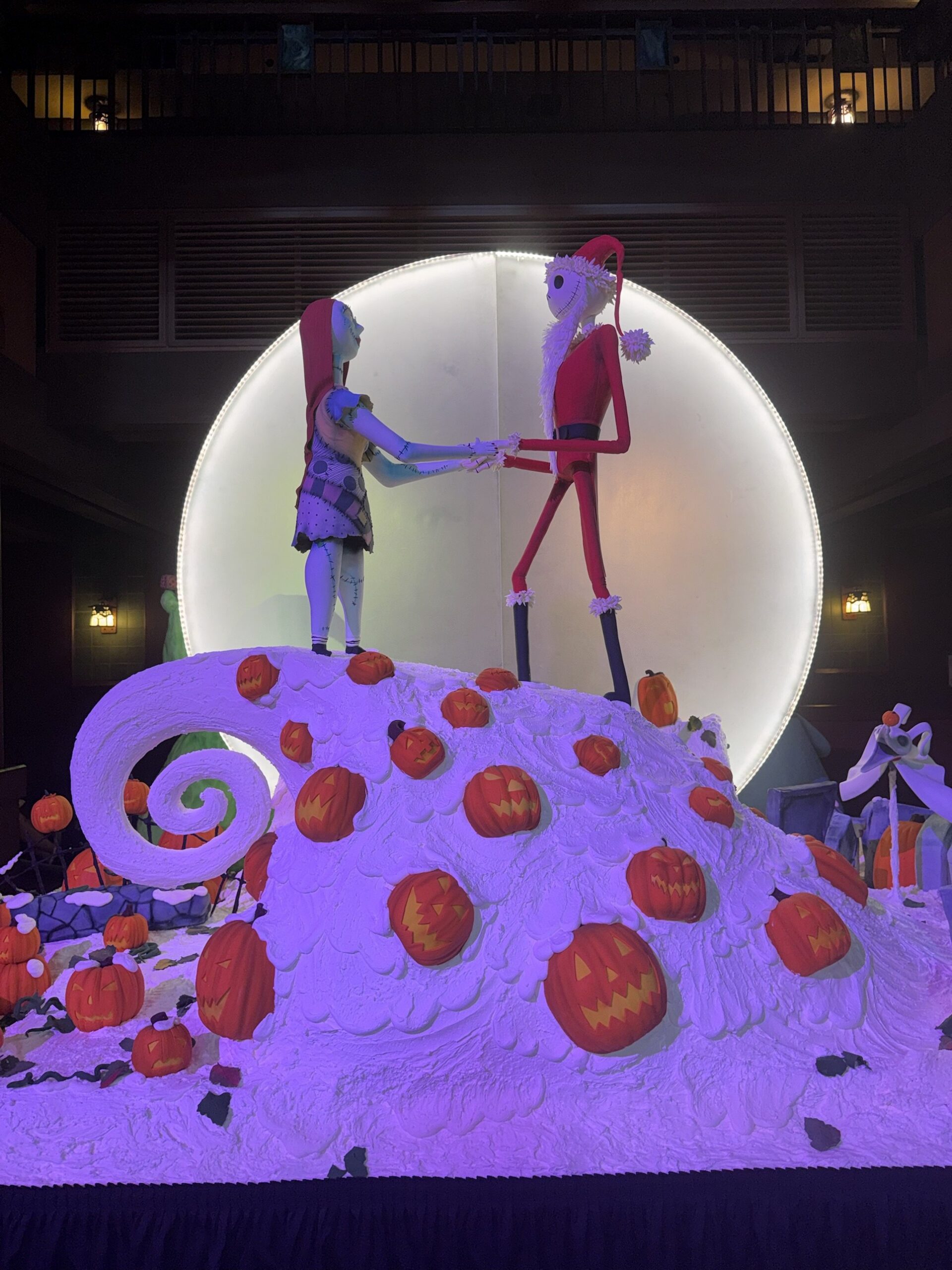 Nightmare Before Christmas confection at Disney's Grand Californian Hotel with Jack in his Sandy Claws suit holding hands with Sally on Spiral Hill in front of a glowing moon, surrounded by jack-o'-lanterns