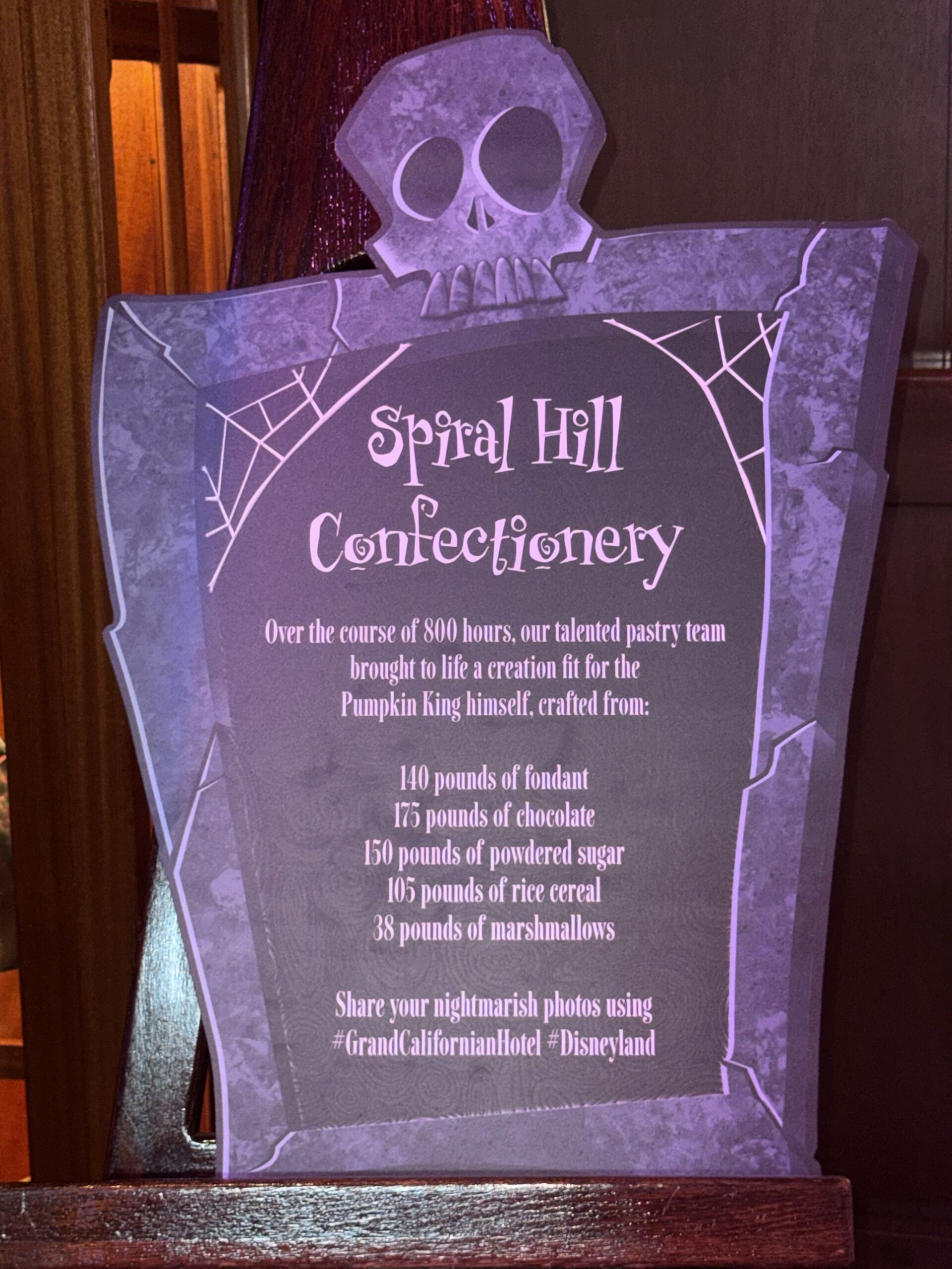 Tombstone-shaped Spiral Hill Confectionery sign listing 800 hours of work and the pounds of fondant, chocolate, powdered sugar, rice cereal and marshmallows used