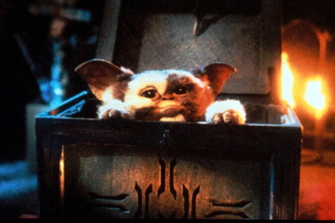 Gizmo peeking out of a wooden box in a still from Gremlins