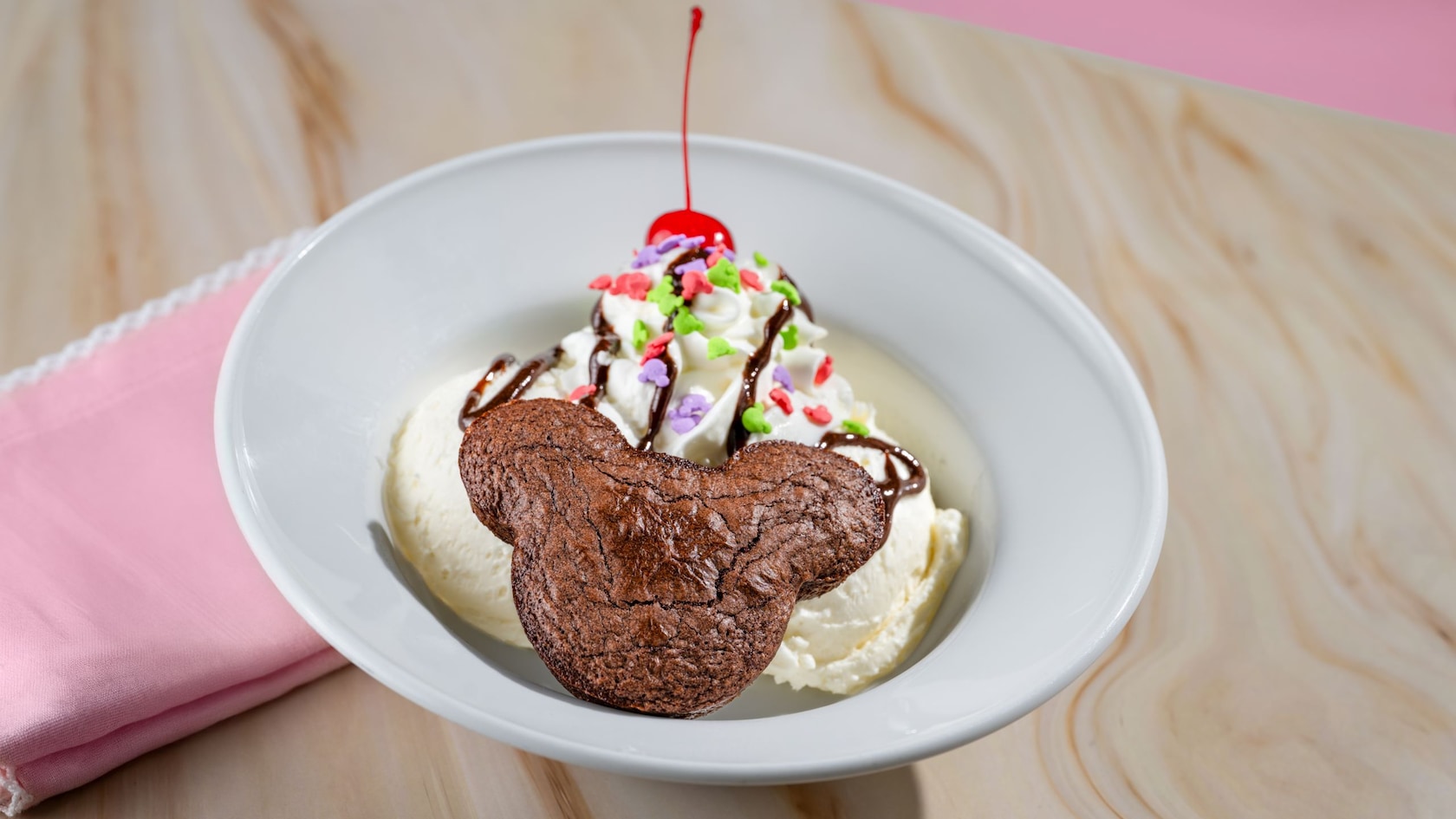 A Mickey Brownie Sundae, which features a brownie shaped like Mickey Mouse in a bowl of ice cream with a cherry, whipped cream and other toppings