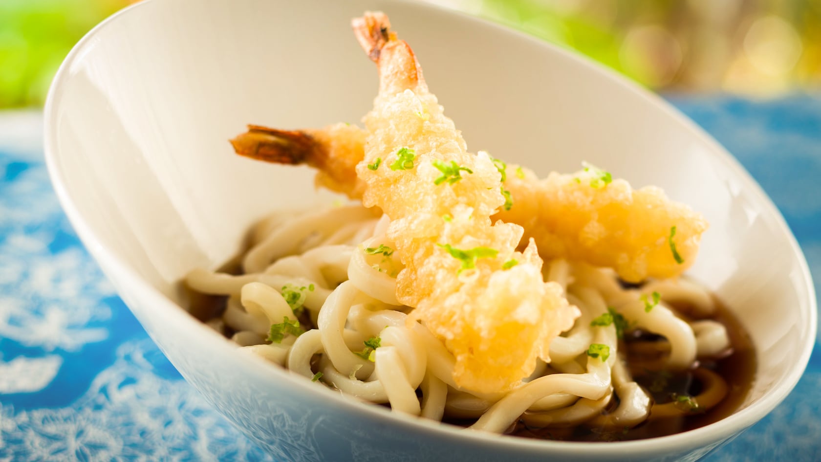 Bowl of udon noodles topped with 2 pieces of tempura shrimp