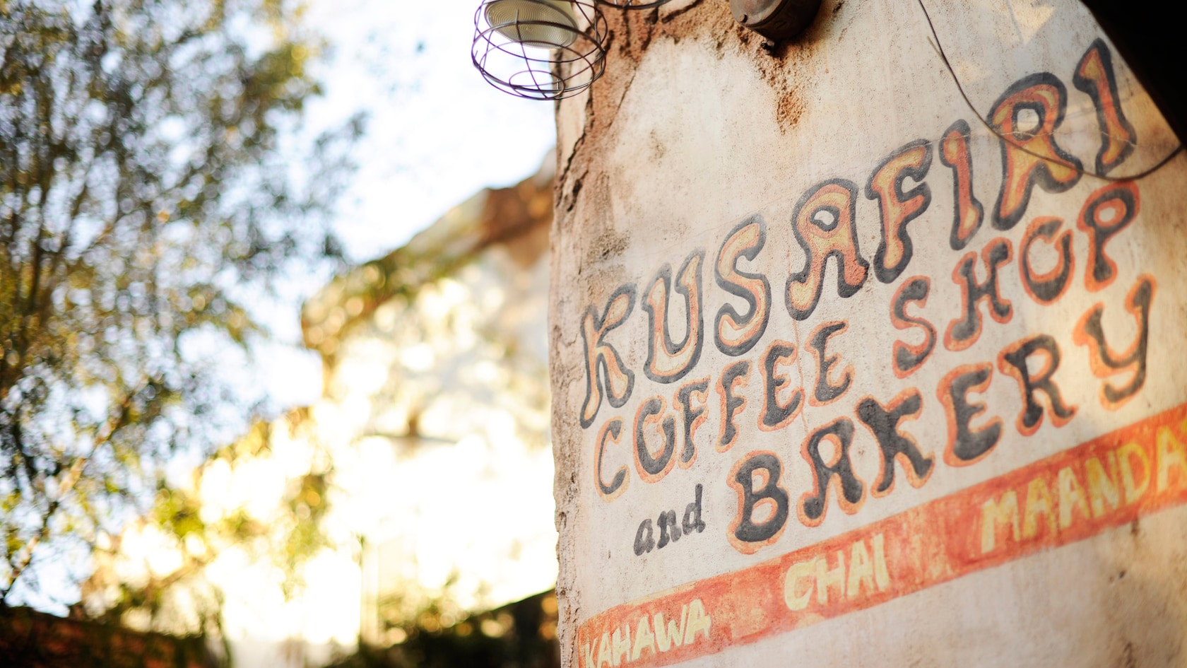 The words Kusafiri Coffee Shop and Bakery painted on a wall