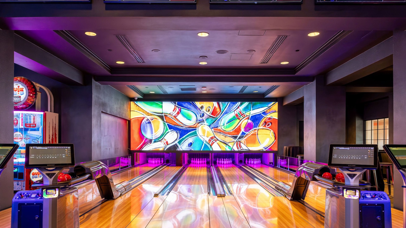 Five bowling lanes at Lagoon Games, Lanes & Eats featuring digital scoreboards and a large screen at the end of the lanes