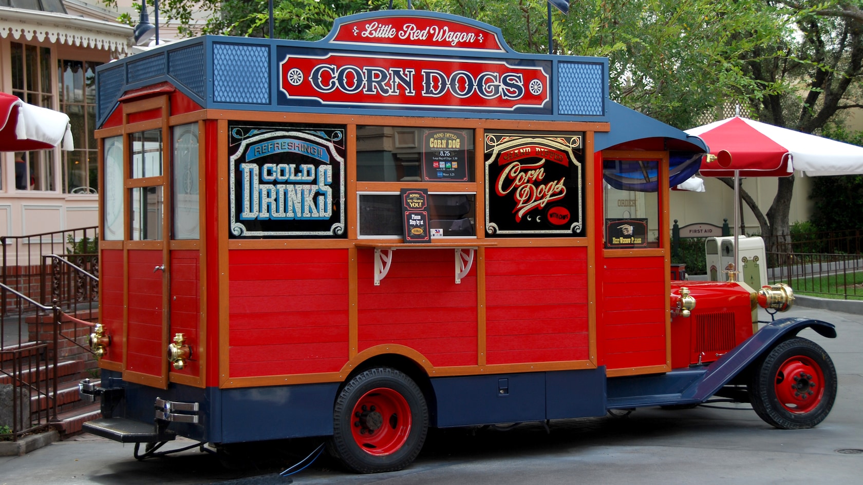 The Little Red Wagon corn dog truck is parked near Main Street USA surrounded by trees