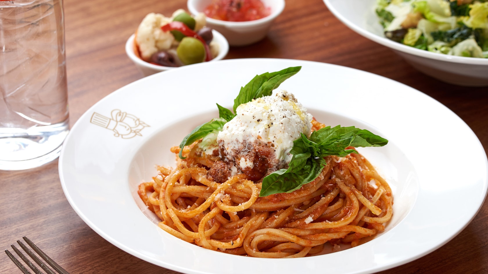 A plate of spaghetti with a side salad