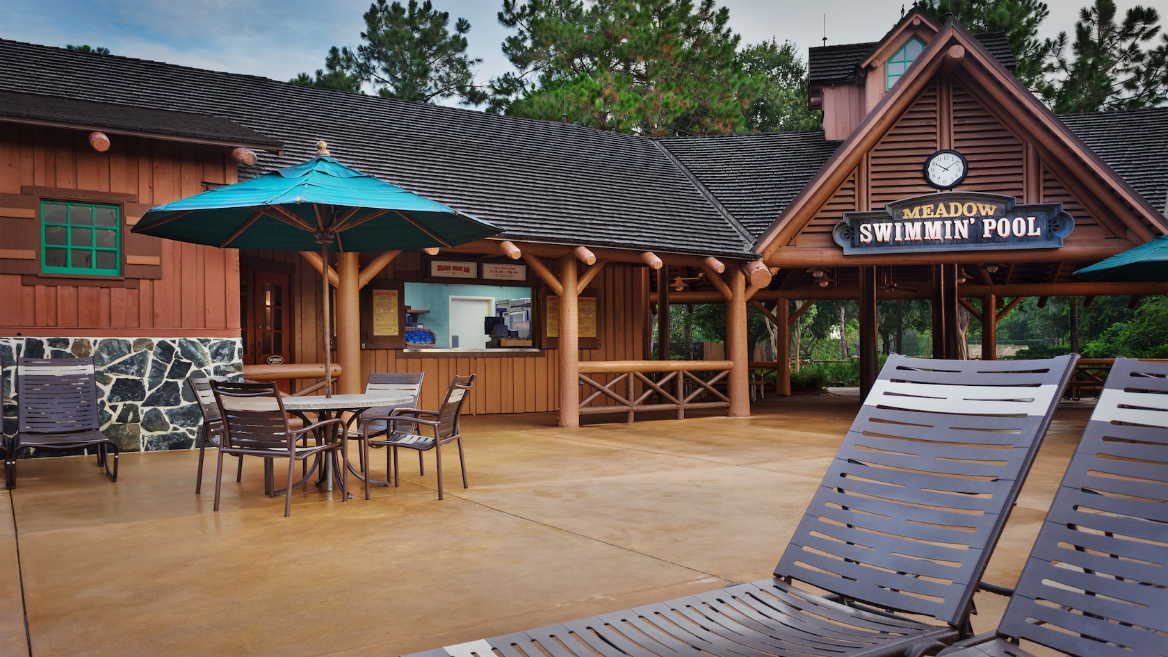 Sun loungers and umbrellaed table on a patio in front of Meadow Snack Bar