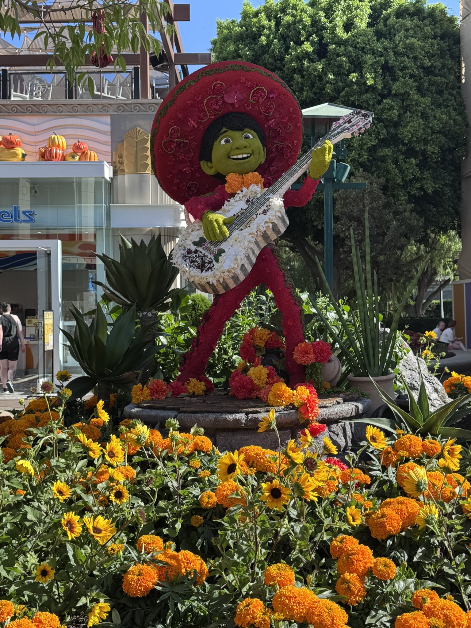 The finished Miguel floral display at Downtown Disney in a red charro suit and sombrero with a white guitar