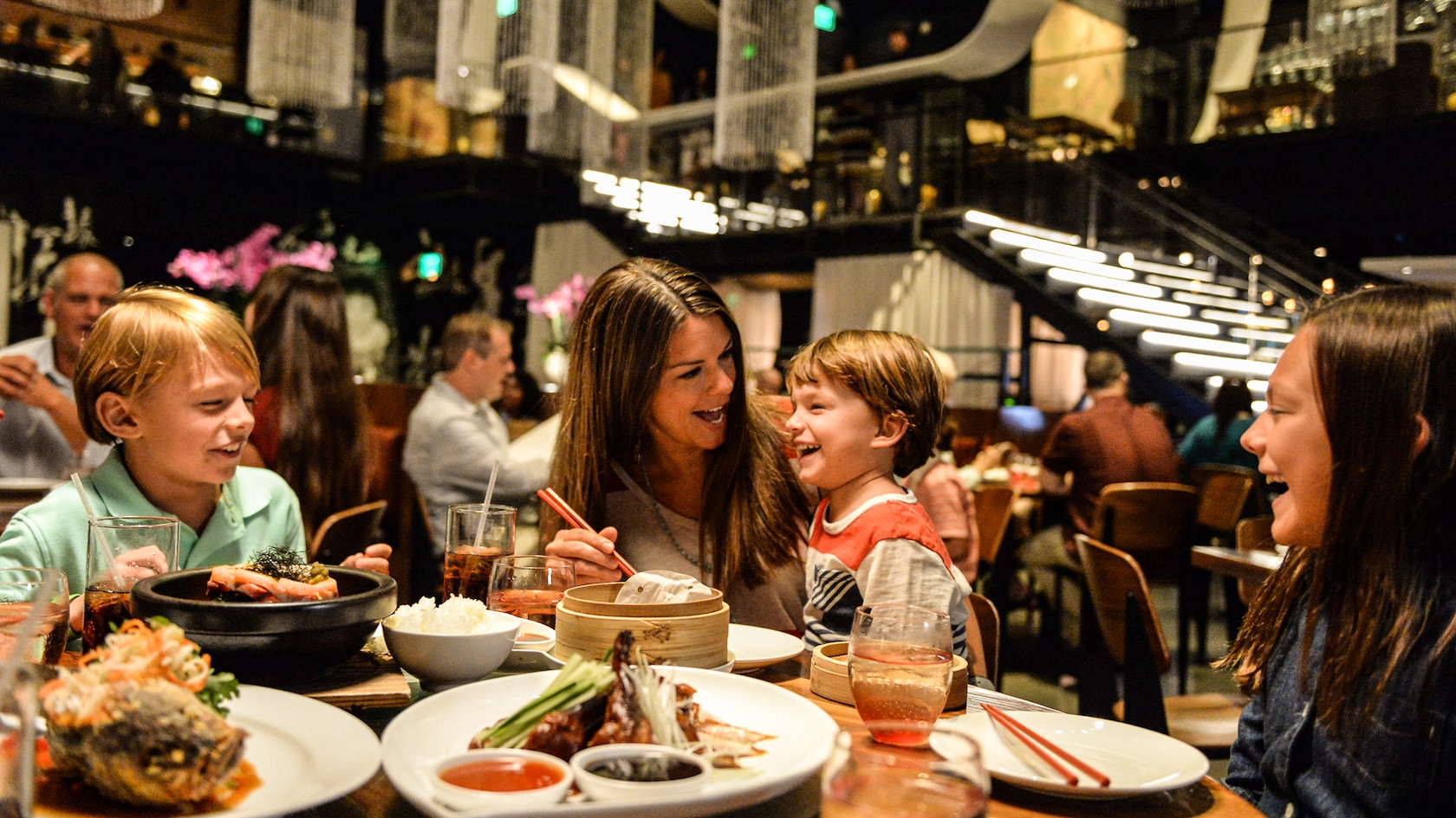 A mother and her 3 children smile while eating in a modern dining room at Morimoto Asia
