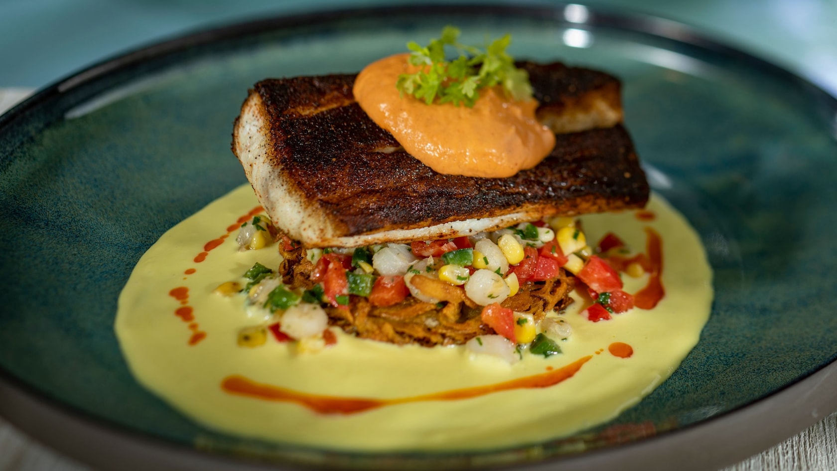 A piece of fish served with corn and other veggies