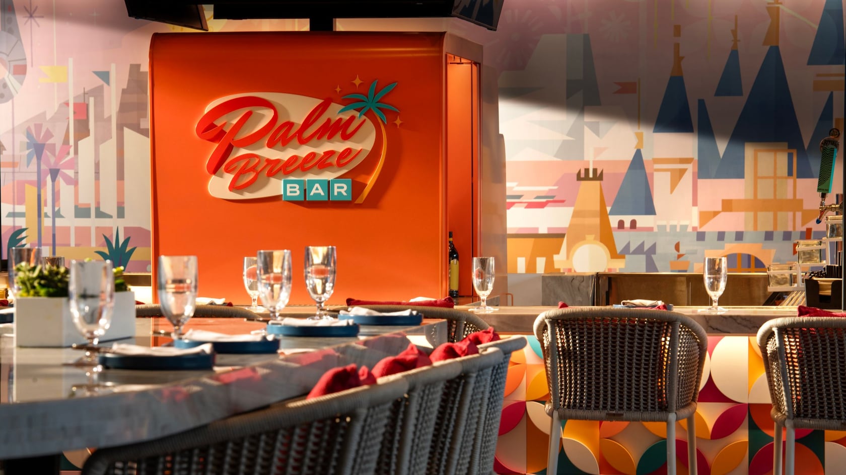 Chairs and place settings at a bar and a table with a sign on the wall that says, 'Palm Breeze Bar'