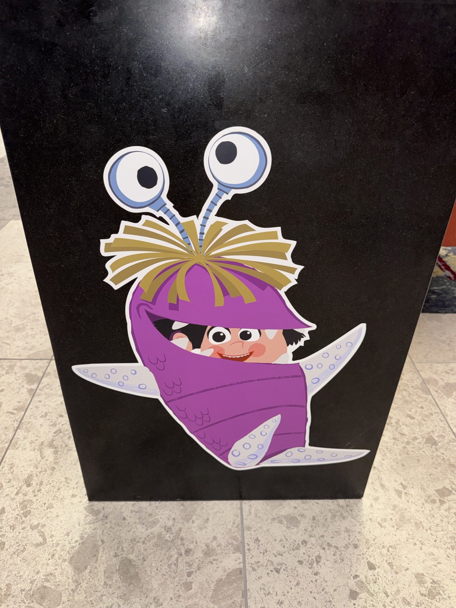 Artwork of Boo in her purple monster costume on a black pedestal at Pixar Place Hotel