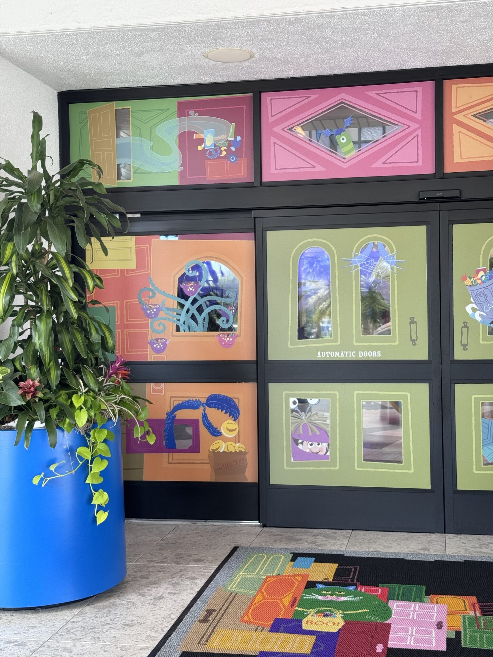 Pixar Place Hotel entrance doors covered in door artwork with tentacles holding candy buckets and Boo peeking through a window