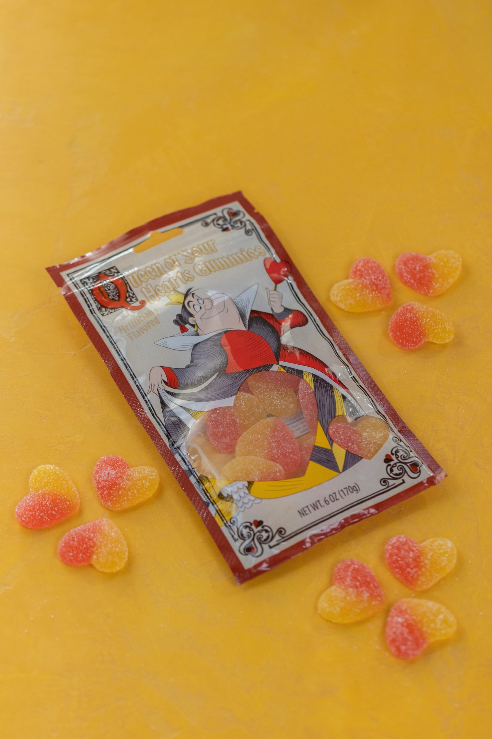 Queen of Sour Hearts Gummies bag with heart-shaped gummies scattered around it