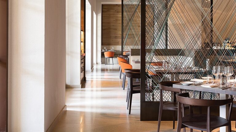 Glittering wine glasses, silver stemware and small plates adorn the dining tables amid modern décor