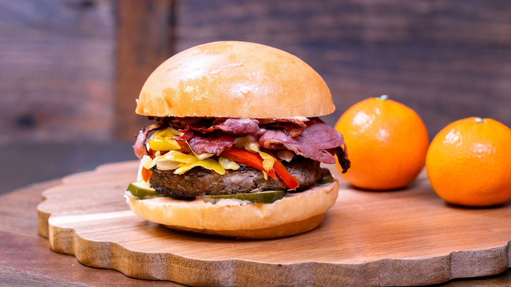 A gourmet burger from the Red Rose Taverne at Disneyland Park, featuring a beef patty, pastrami, cheese, pickles, sauteed onions and aioli sauce