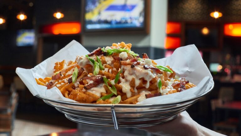A basket of French fries loaded with cheese, chives and ranch dressing