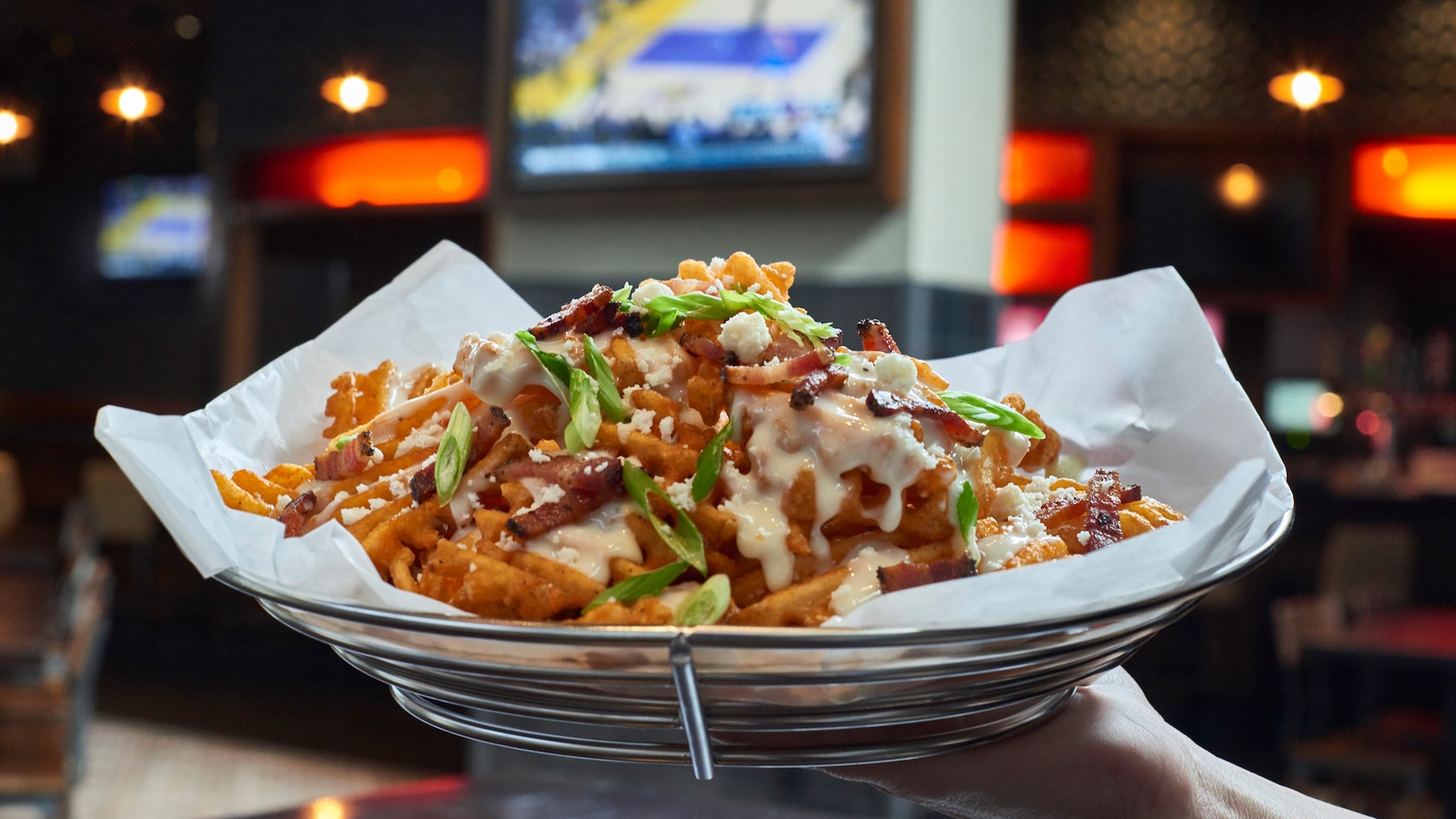 A basket of French fries loaded with cheese, chives and ranch dressing