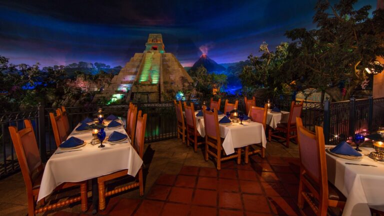 Tables near trees and Mayan pyramid with volcano in background