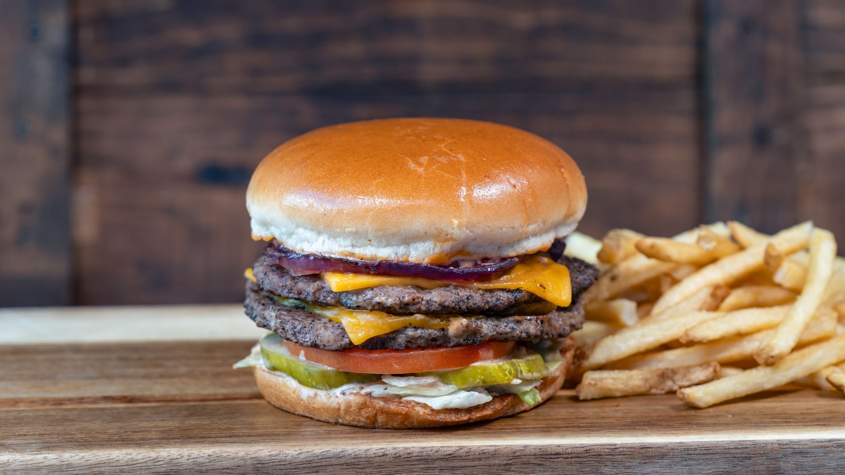 A double cheeseburger next to a pile of french fries