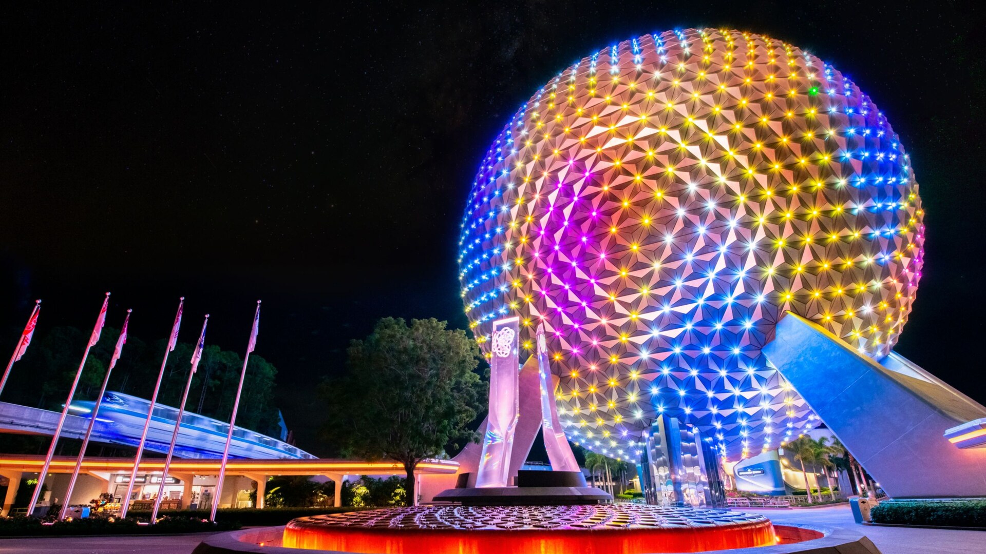 Spaceship Earth at EPCOT lit up in rainbow colors at night