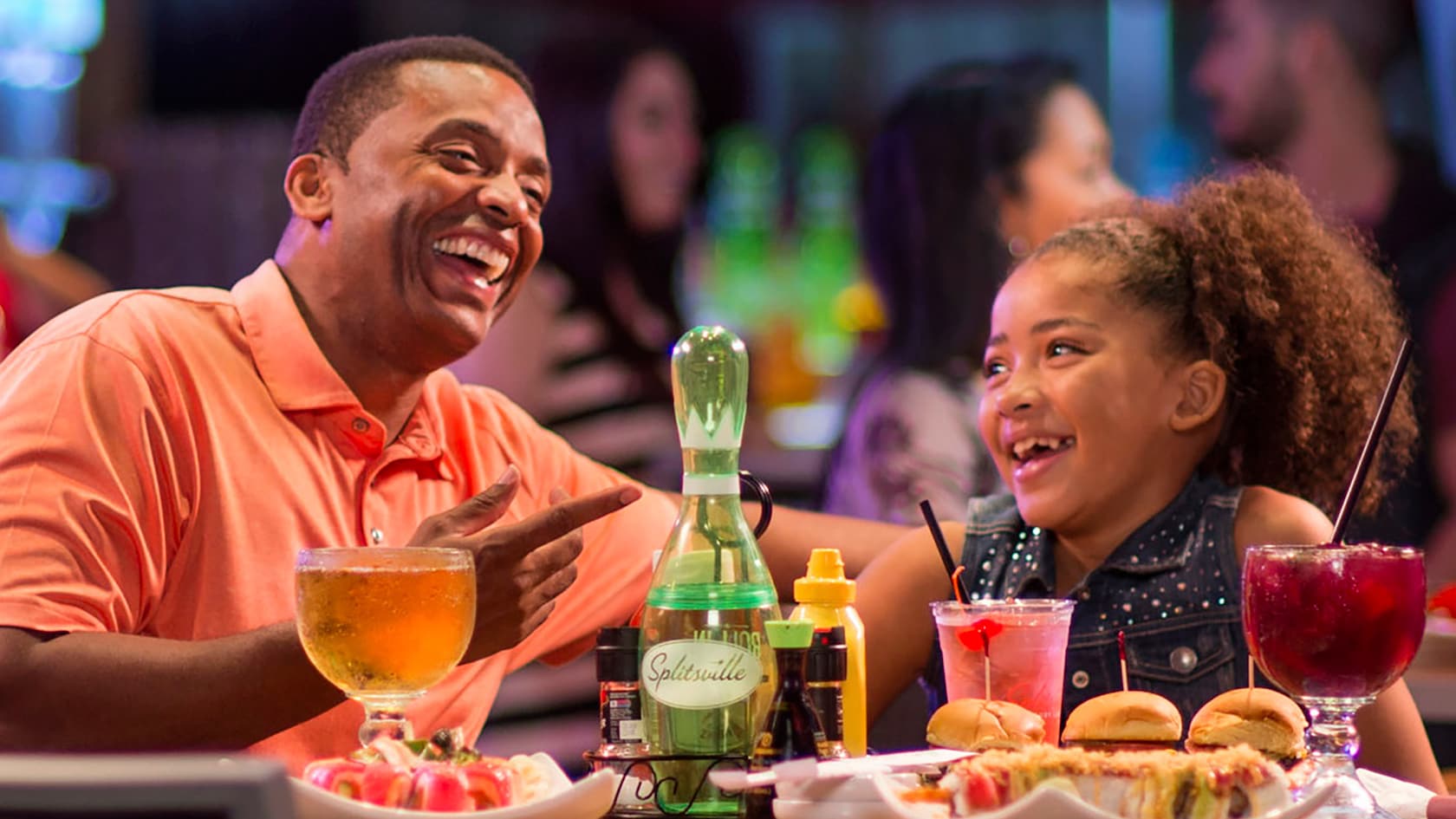 A father and his young daughter enjoy food and beverages at the Splitsville Dining Room