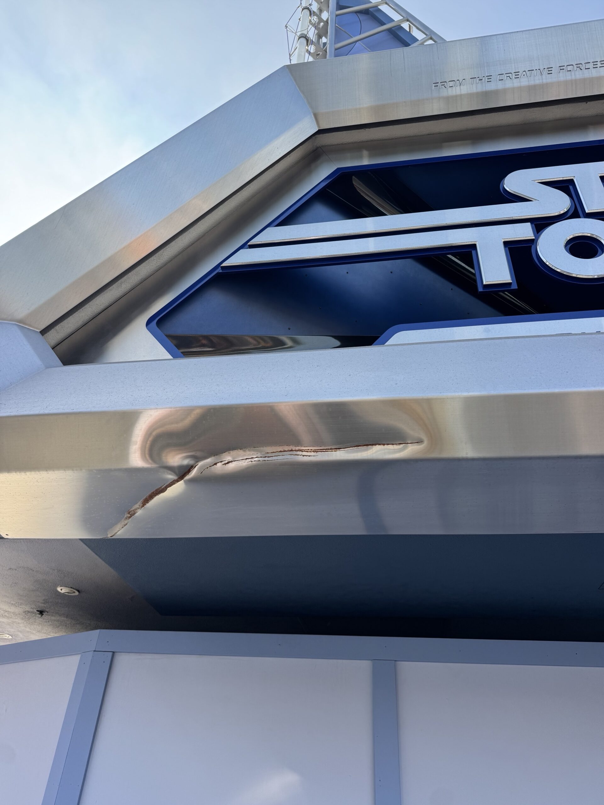 A long dent and scrape across the brushed steel frame of the Star Tours sign at Disneyland