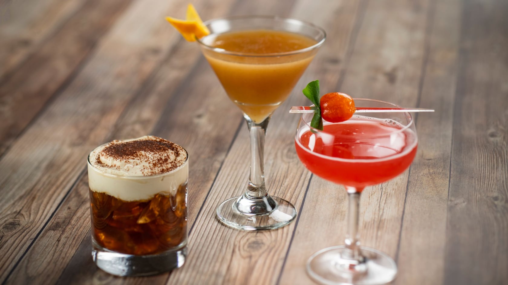 3 unique cocktails atop a wood table