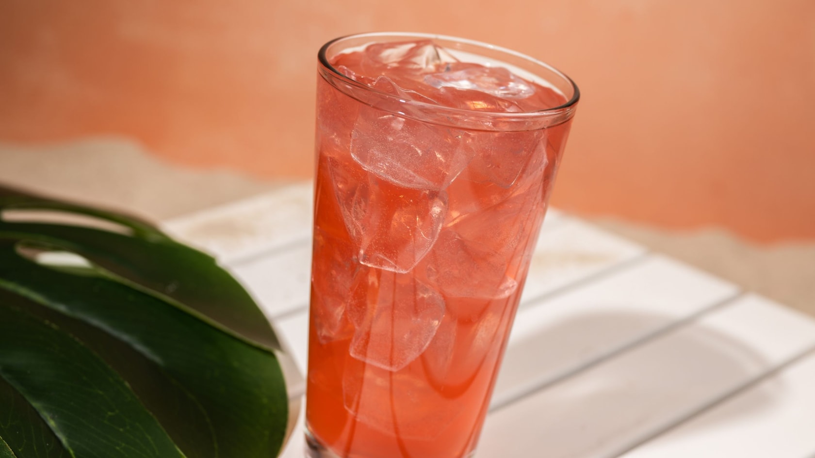 A Strawberry Lemonade Moonshine drink sitting on a table next to a plant