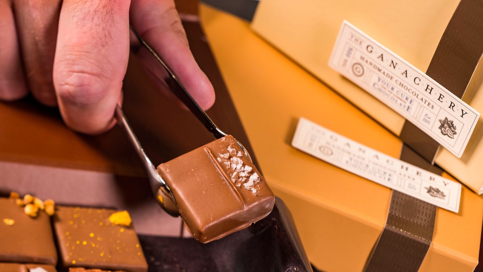 A ganache square being picked up with tongs