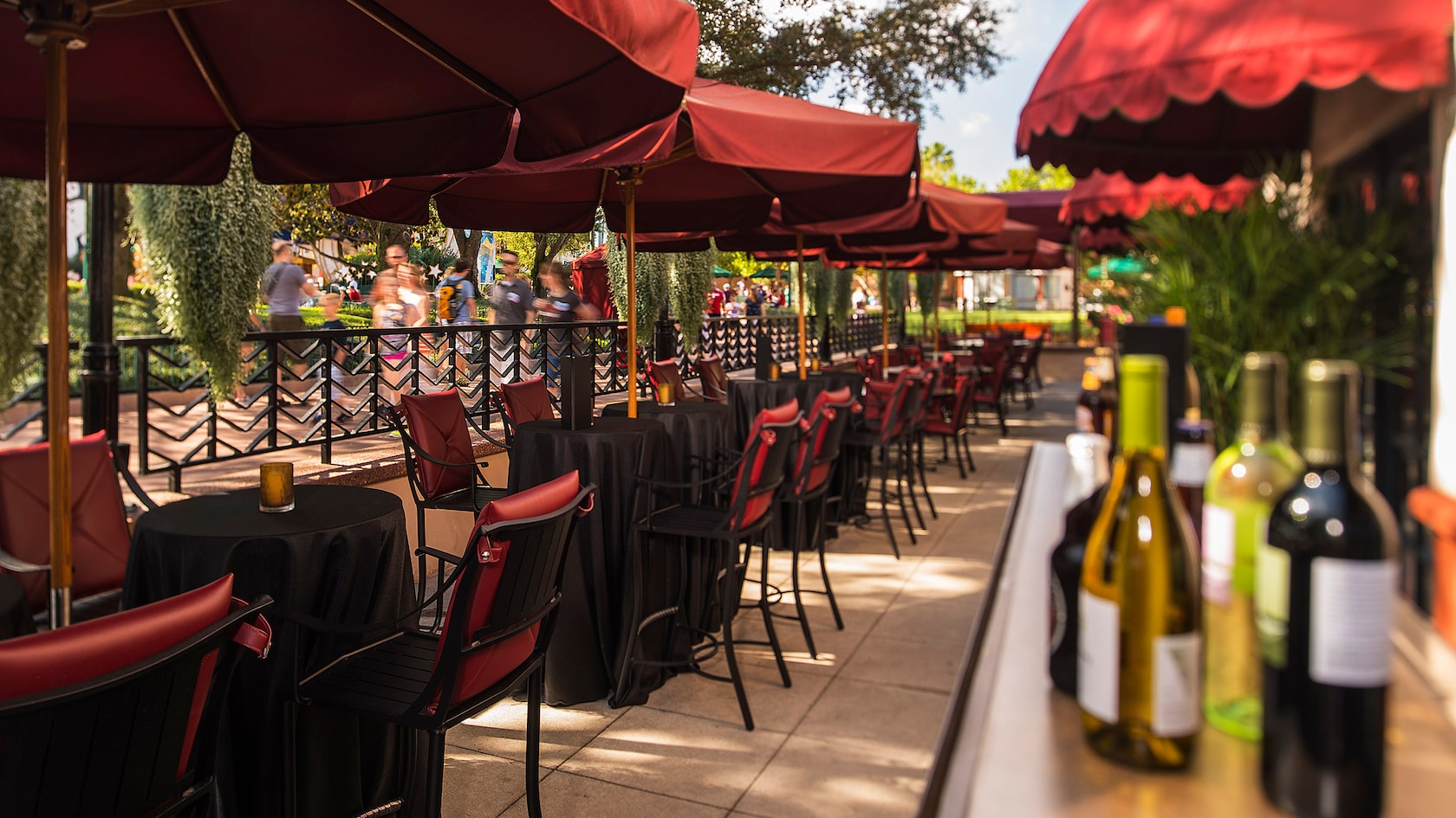 People pass by the railing of an outdoor bar