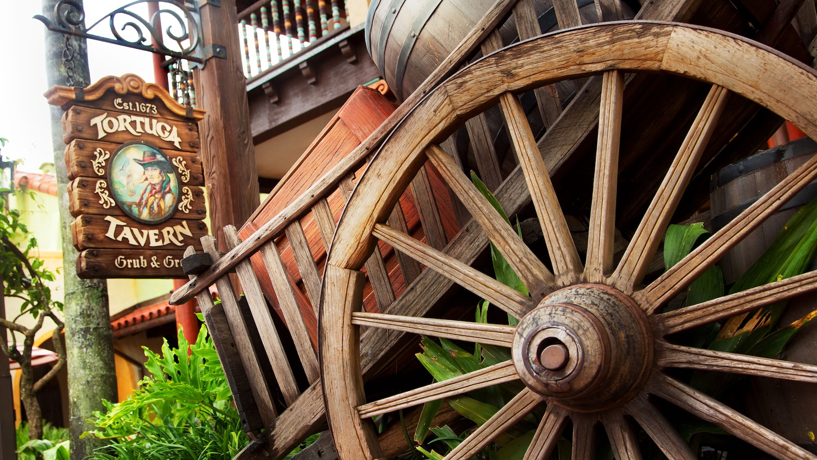 Outdoor signage for Tortuga Tavern by a large wagon wheel