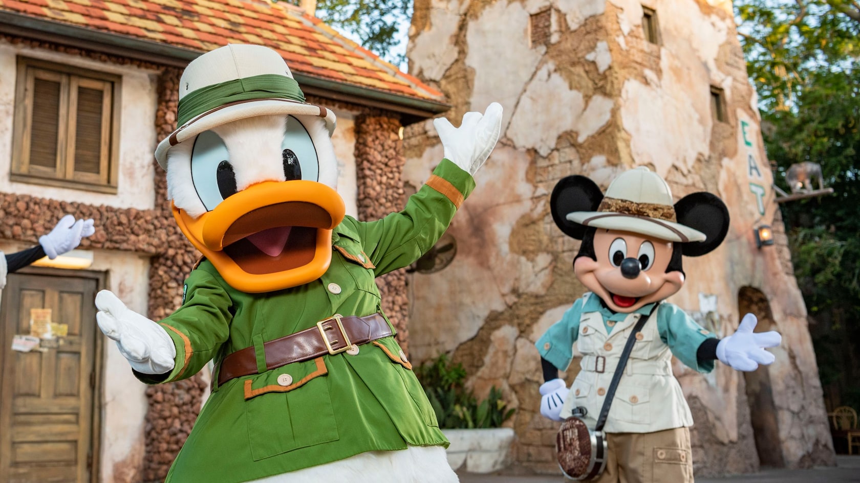 Goofy, Donald Duck and Mickey Mouse dressed in safari gear while standing in front of Tusker House Restaurant