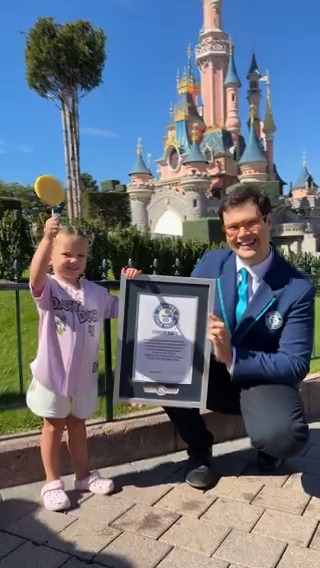 Bootsie Darrington holding her Guinness World Records certificate in front of Sleeping Beauty Castle at Disneyland Paris